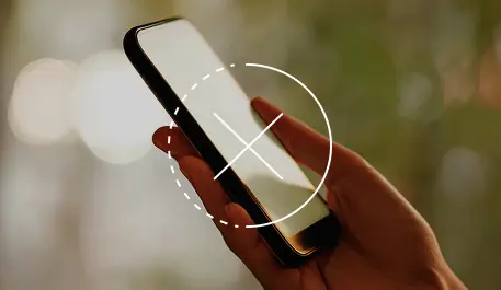 Hand holding a smartphone with a blurred background, screen showing an overlay of a crossed-out circle symbol.